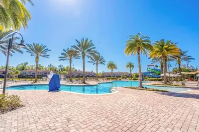 a swimming pool with palm trees in a resort at Private Spa Townhome at Regal Oaks Resort in Orlando