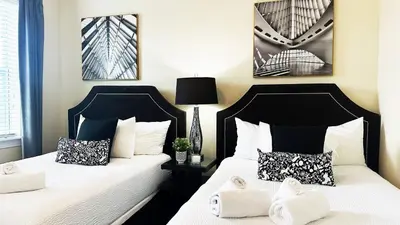 two beds in a bedroom with white sheets and pillows at 11 bd home Movie Room Close to Disney Sleeps 24 in Orlando
