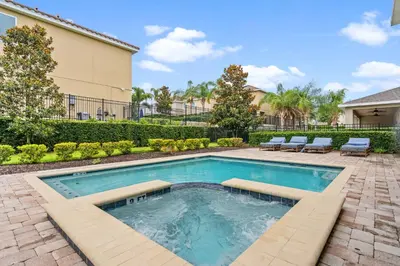 a swimming pool in a yard with chairs and a house at 11 bd home Movie Room Close to Disney Sleeps 24 in Orlando