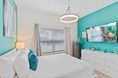 a bedroom with a white bed and a blue wall at 2452 Reading Trail in Kissimmee