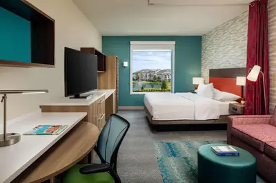 a hotel room with a bedroom with a bed and a tv at Home2 Suites By Hilton Lake Mary Orlando in Lake Mary