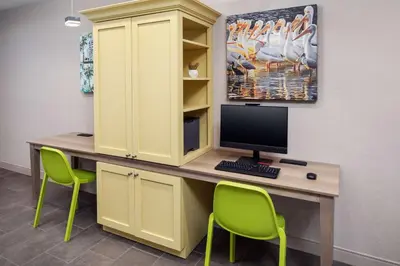 a desk with a computer and two green chairs at Home2 Suites By Hilton Lake Mary Orlando in Lake Mary