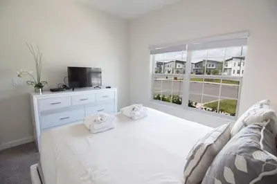 a white bedroom with a bed and a window at Private Pool Townhome at Storey Lake Resort in Kissimmee