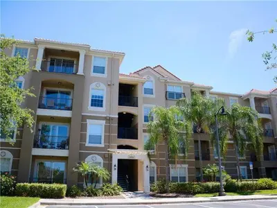 a large building with palm trees in front of it at Apartment at Vista Cay Resort in Orlando