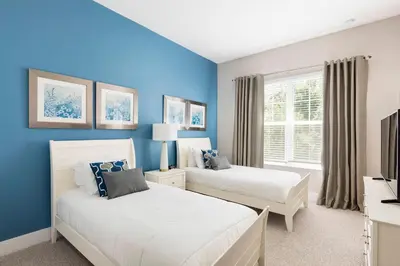 two beds in a bedroom with blue walls at GORGEOUS 5 Suites Villa at Summerville Resort in Orlando
