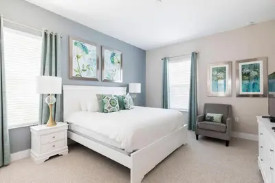 a bedroom with a white bed and a chair at GORGEOUS 5 Suites Villa at Summerville Resort in Orlando