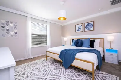 a white bedroom with a large bed and a window at Amazing 3BedroomsNear to DisneyThemed rooms in Kissimmee