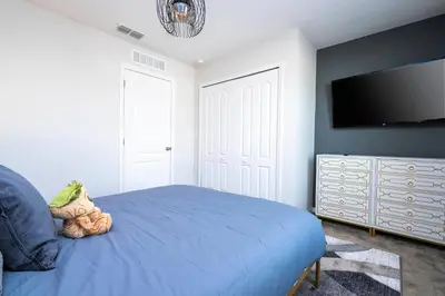 a bedroom with a blue bed and a flat screen tv at Amazing 3BedroomsNear to DisneyThemed rooms in Kissimmee