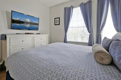 a bedroom with a bed and a tv on a dresser at Sunny Condo Retreat at Windsor Hills in Orlando