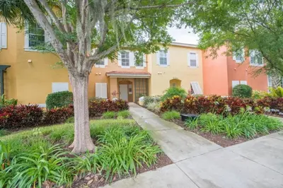 a building with a tree and a sidewalk in front at Townhome at Emerald Island Resort in Kissimmee