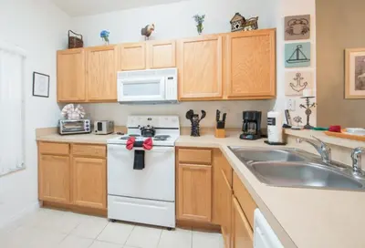 a kitchen with wooden cabinets and a white appliance at Townhome at Emerald Island Resort in Kissimmee