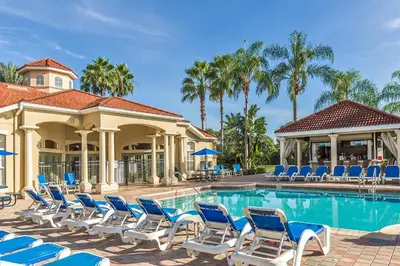 a resort pool with blue chairs and palm trees at Townhome at Emerald Island Resort in Kissimmee