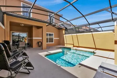 a swimming pool on a patio with chairs and a house at 3069 Beach Palm in Kissimmee