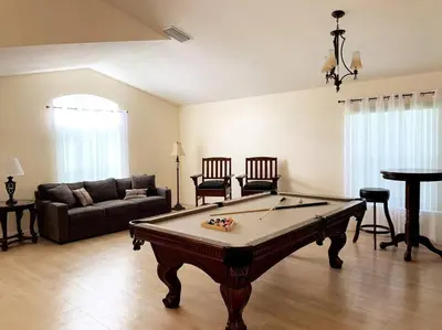 a living room with a pool table and a couch at Minutes to Disney! Spacious Home w/ Private Pool, Themed Rooms! in Orlando