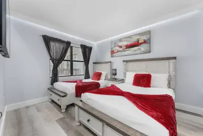 two beds in a white bedroom with red pillows at Exclusive Second-Floor Apartment in Orlando