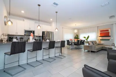 a kitchen and living room with a bar with chairs at Free Waterpark 5Bd Close to Disney Private Pool 2497 in Kissimmee