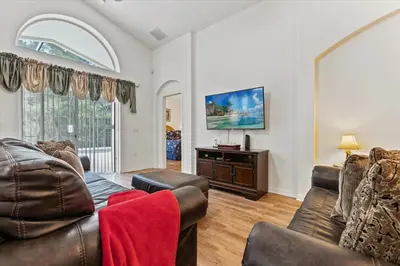 a living room with leather furniture and a large window at 4676 Cumbrian Lakes in Kissimmee