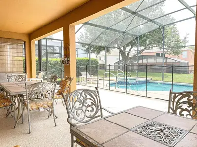 a patio with a table and chairs and a swimming pool at EIR8505PH - Emerald's paradise by Disney in Kissimmee