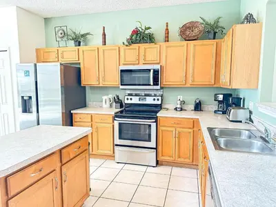 a kitchen with wooden cabinets and stainless steel appliances at EIR8505PH - Emerald's paradise by Disney in Kissimmee