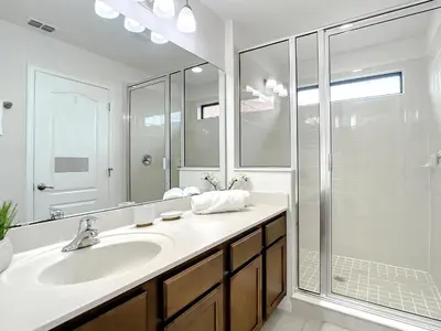 a white bathroom with a sink and a shower at Tranquility Hut, Spacious 4-bedrooms, 4-bathrooms, Pools, free parking in Kissimmee