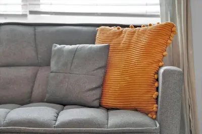 an orange pillow sitting on a gray couch at 3151 Paradox #306 in Kissimmee