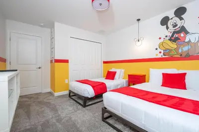a bedroom with two beds and a mickey mouse painting on the wall at Brand New Cozy Retreat at Storey Lake Resort in Kissimmee