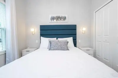a white bed with a blue headboard in a bedroom at Stunning 5 Bd w Pool at Storey Lake Resort 2400 in Kissimmee