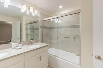 a bathroom with two sinks and a glass shower at Family 4BR w Private Pool near Disney Parks in Kissimmee