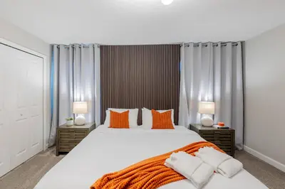 a bedroom with a large white bed with orange pillows at Family 4BR w Private Pool near Disney Parks in Kissimmee
