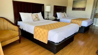a hotel room with two beds and a chair at Hotel Monte Carlo in Kissimmee