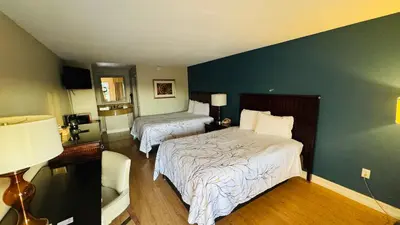a bedroom with two beds and a blue wall at Hotel Monte Carlo in Kissimmee