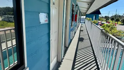a porch of a blue building with a window at Hotel Monte Carlo in Kissimmee