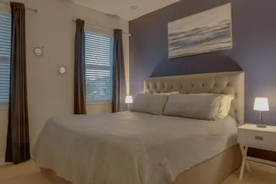 a bedroom with a large bed and two windows at Summer Escape - Spacious 8BR Home with Private Pool! in Kissimmee