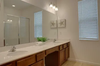 a bathroom with two sinks and a large mirror at Summer Escape - Spacious 8BR Home with Private Pool! in Kissimmee