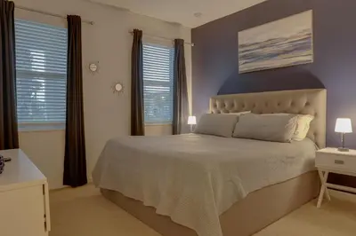 a bedroom with a large bed and two windows at Summer Escape - Spacious 8BR Home with Private Pool! in Kissimmee