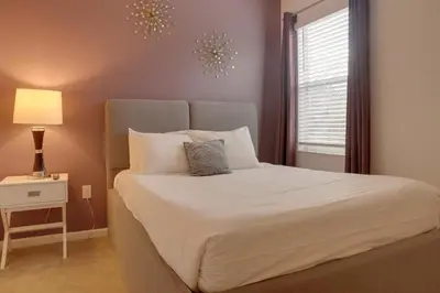 a bedroom with a large white bed with a window at Summer Escape - Spacious 8BR Home with Private Pool! in Kissimmee