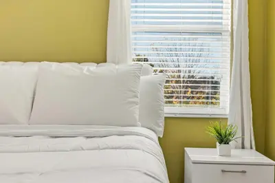 a bedroom with a white bed and a window at Sunny Stay in Orlando - 6BR Home with Pool! in Kissimmee