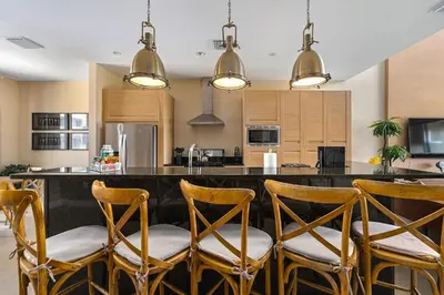 a kitchen with a bar with wooden stools at 4 BR Home w/ Resort Amenities + 3 Mi to Disney in Orlando