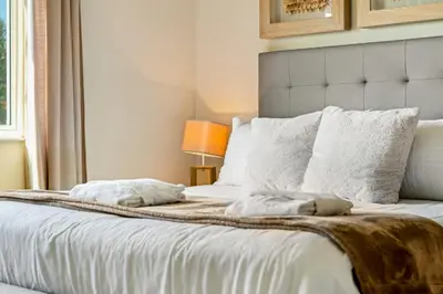 a bedroom with a bed with white sheets and pillows at 4 BR Home w/ Resort Amenities + 3 Mi to Disney in Orlando