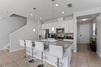 a kitchen with white cabinets and a bar with stools at Amazing 4BdrmsPrivate Hot Tub7 miles from Disney in Kissimmee