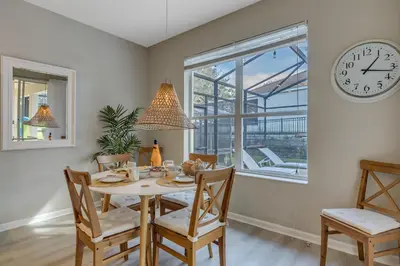 a dining room with a table and chairs and a clock at Hibiscus Villa in Orlando