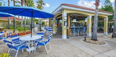 a patio with blue chairs and a table and umbrella at Serene Stay at Terra Verde Resort by Shine Villas 111 townhouse in Kissimmee
