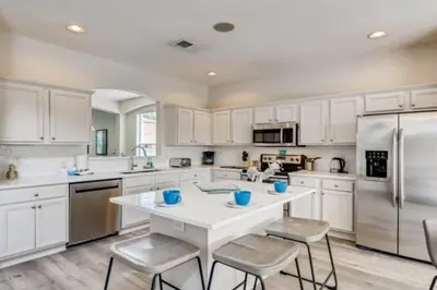 a kitchen with white cabinets and a white table and chairs at Lakefront 6BR Resort Pool Home Near Disney in Kissimmee