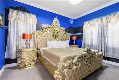 a bedroom with a gold bed and blue walls at Enchanting a Magical Orlando Trip in Kissimmee