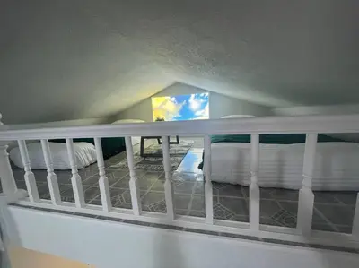a bedroom with two beds and a white railing at The Tiny Cottage in the Springs/ Central FL in Altamonte Springs