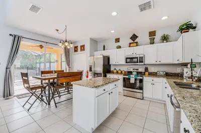a kitchen with white cabinets and a dining room with a table at 7 Mi to Disney Kissimmee Home with Pool and Hot Tub! in Kissimmee