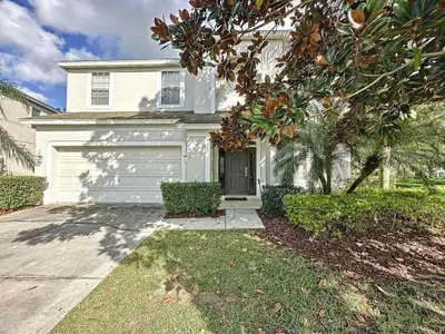 a white house with a garage at This amazing 6 Bedroom property with a lake view in Orlando