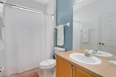 a bathroom with a sink and a toilet and a mirror at Immaculate 4 bedrooms 3 bathroom in Windsor Palms in Kissimmee