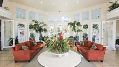 a living room with two couches and a table with flowers at Immaculate 4 bedrooms 3 bathroom in Windsor Palms in Kissimmee