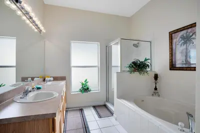 a bathroom with a tub and a sink and a tub and a bath tub at Tropical and peaceful, this 5 bed with Pool & Spa in Orlando